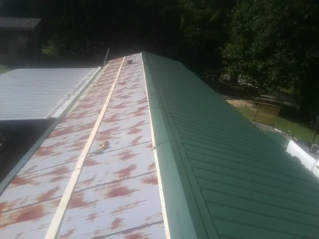 Old rusted panels beside newly installed green metal roofing — Wind Damage Roof Repair by Roofing Brothers in Hazlehurst
