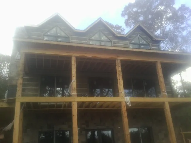 Dormers and porch framing on a large log home under construction — Roof Coating work by our crew in Hazlehurst