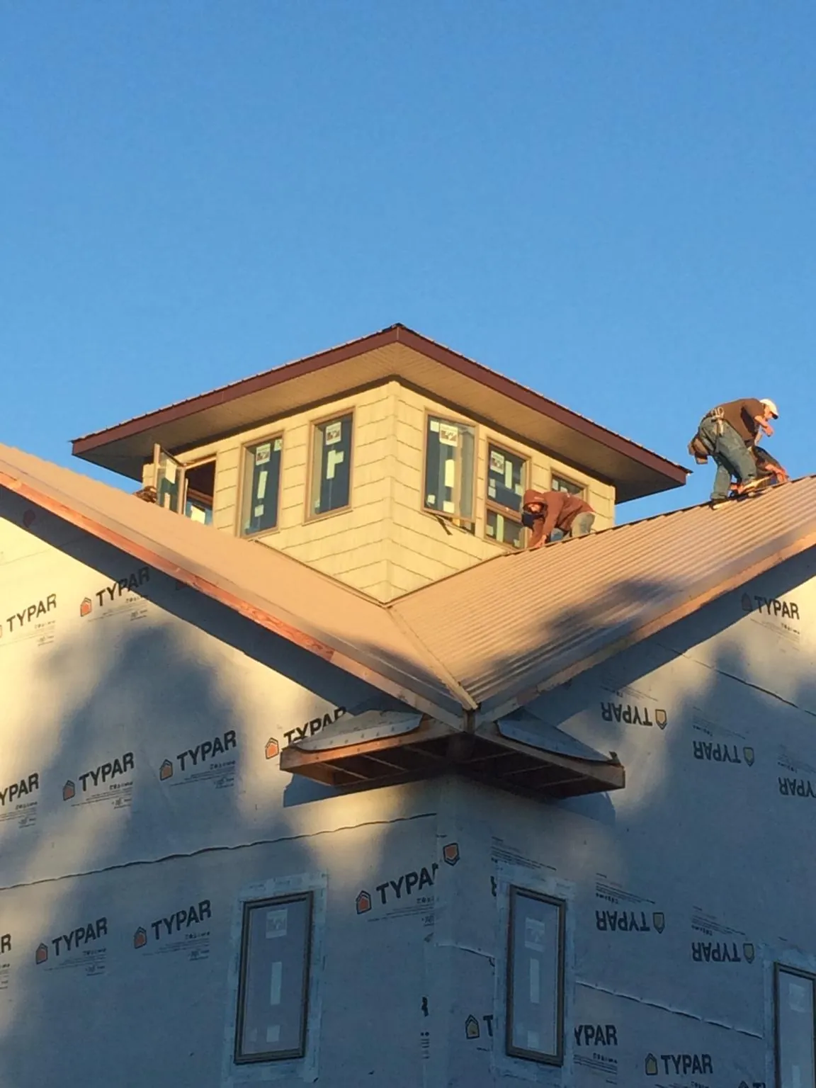 Roofers working around a rooftop cupola on a new metal roof at sunset — Roof Waterproofing in Hazlehurst by Roofing Brothers